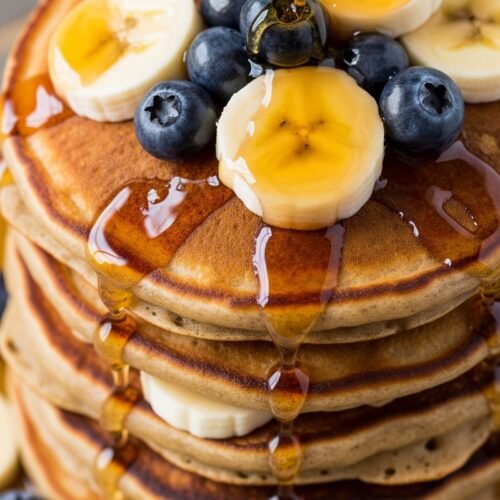 Close up image of banana pancakes with syrup and berries