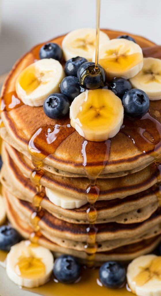 Close up image of banana pancakes with syrup and berries