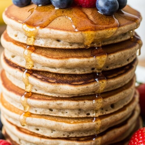 Healthy pancakes pile on a plate with berries syrup